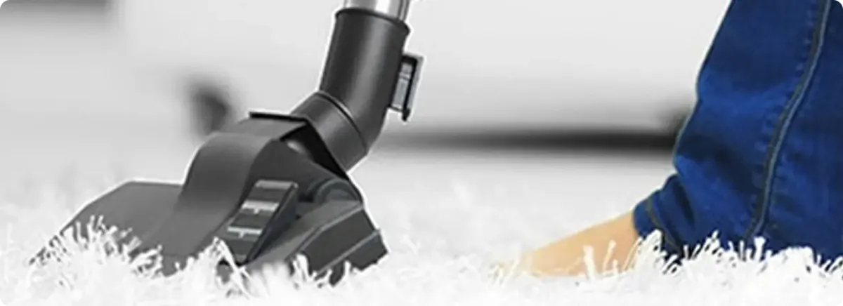 Close-up of a professional vacuuming a white carpet in Maize.