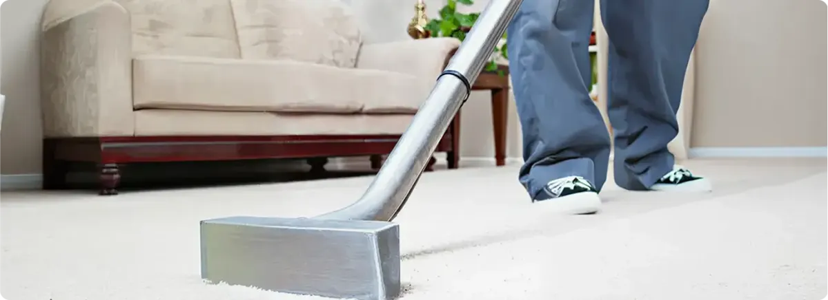 Carpet cleaning technician using a hot-water extraction wand on a light-colored carpet in a living room, Wichita, KS.