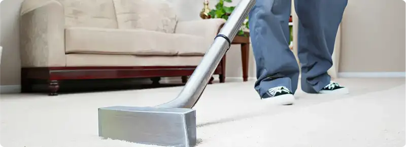 Carpet cleaning technician using a hot-water extraction wand on a light-colored carpet in a living room, Wichita, KS.