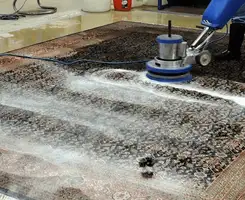Professional rug cleaning with a rotary floor machine and shampoo foam, deep-cleaning an area rug, in Wichita, KS.