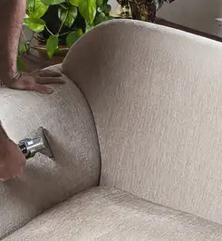 Professional upholstery cleaner deep-cleaning a fabric sofa with a handheld extraction tool and hose Wichita, KS.